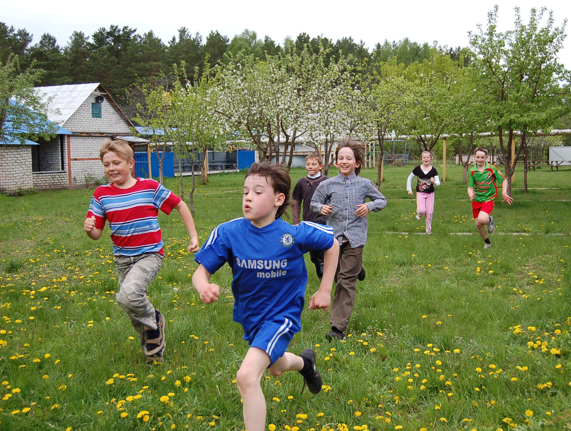 Children running across a green meadow in the schoolyard during spring
