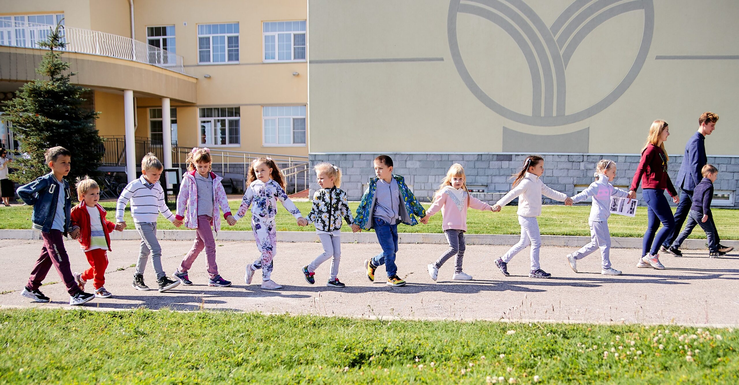 Children walking hand in hand along the path near the school building