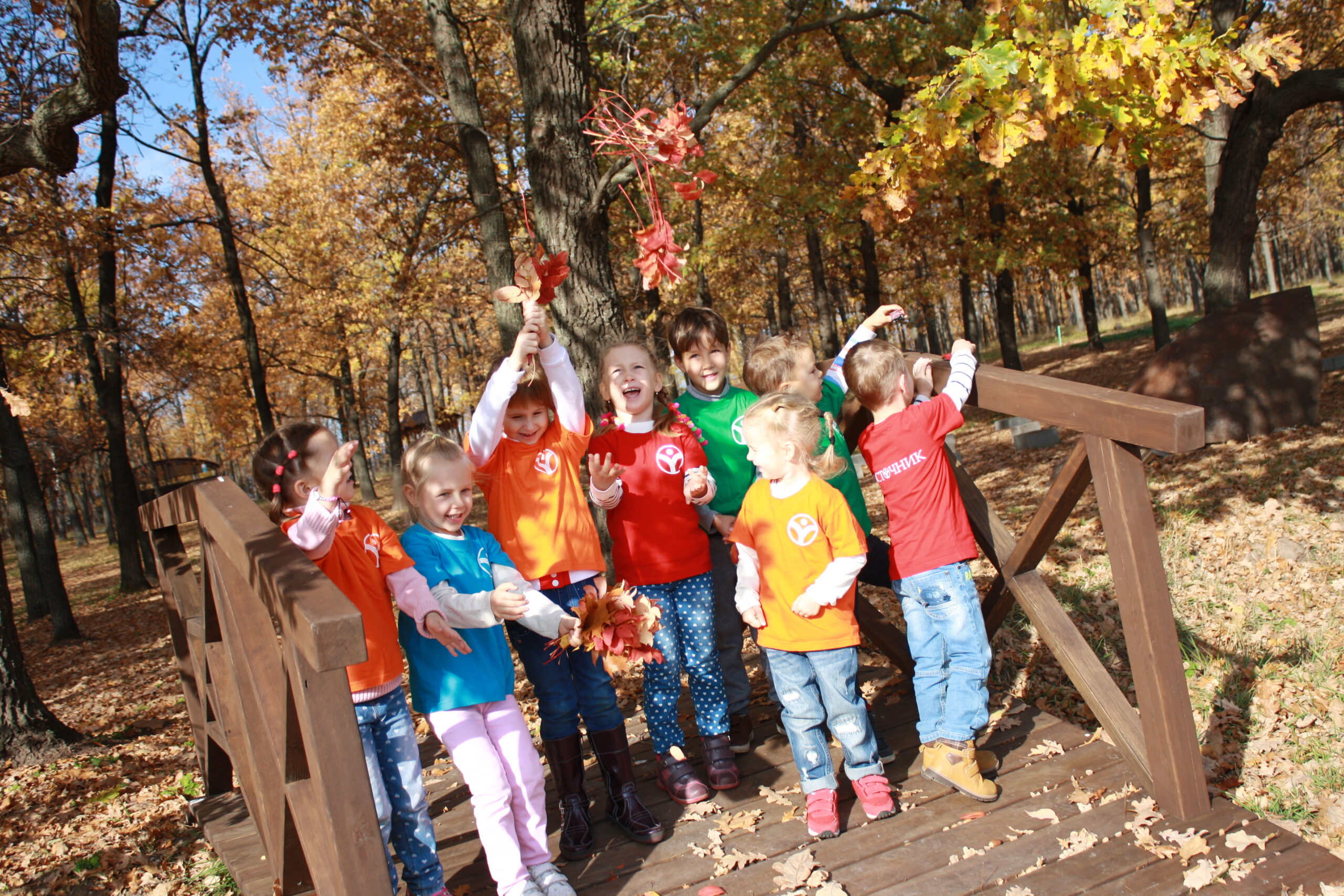 Children playing on a wooden bridge in an autumn park near school