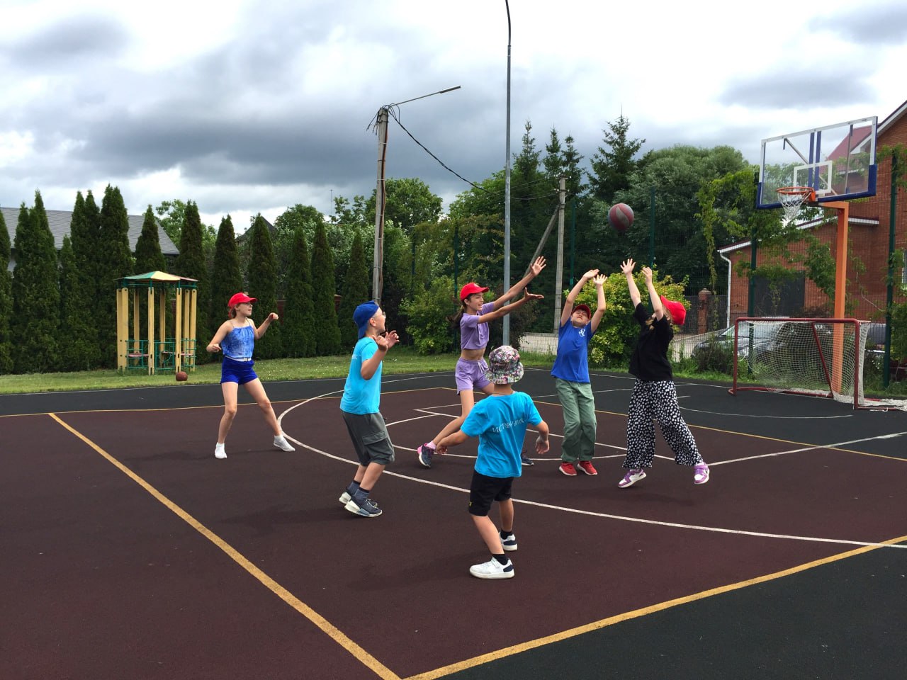 Children playing basketball on an outdoor sports court at the camp
