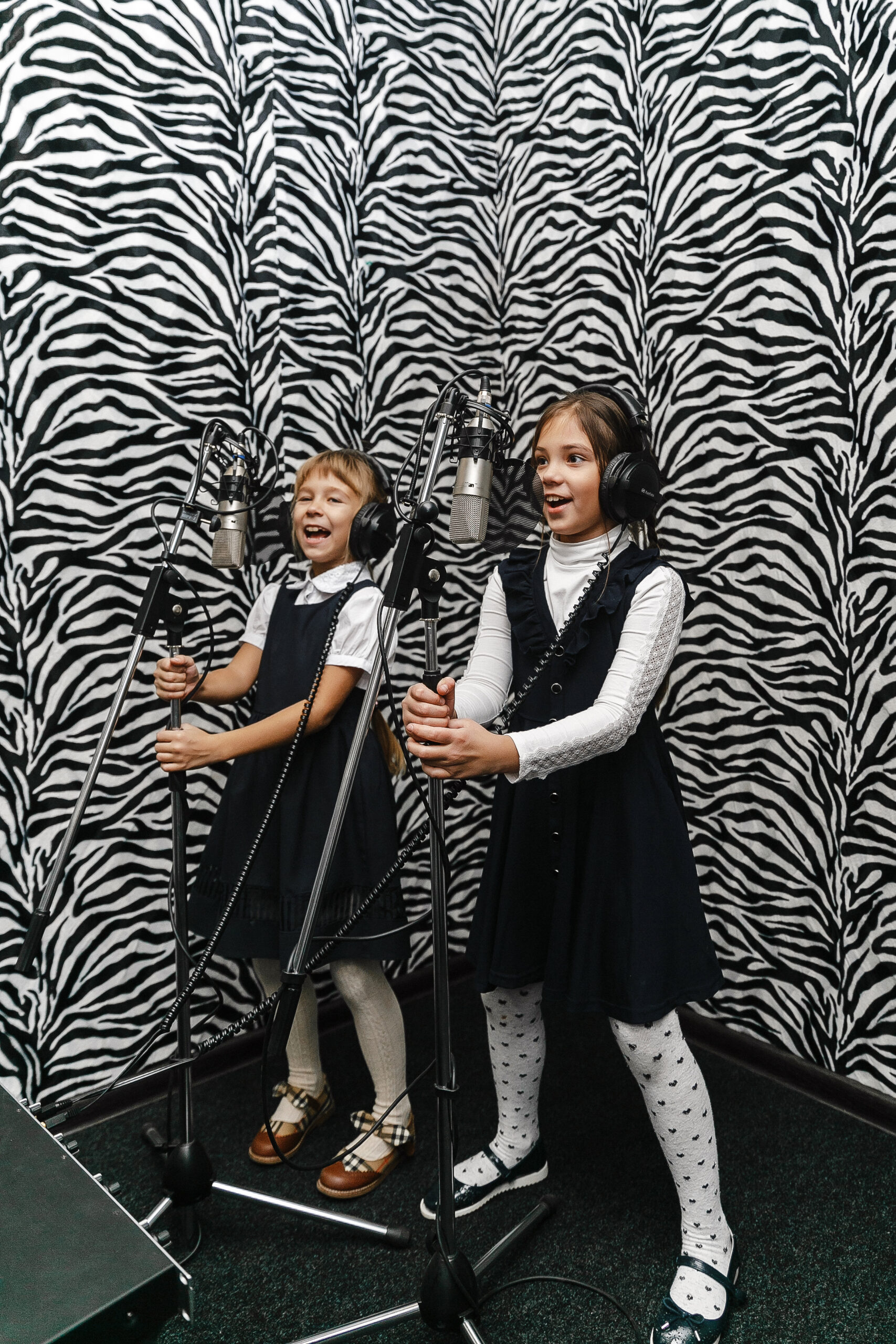 Children singing in a recording studio with microphones and headphones at school