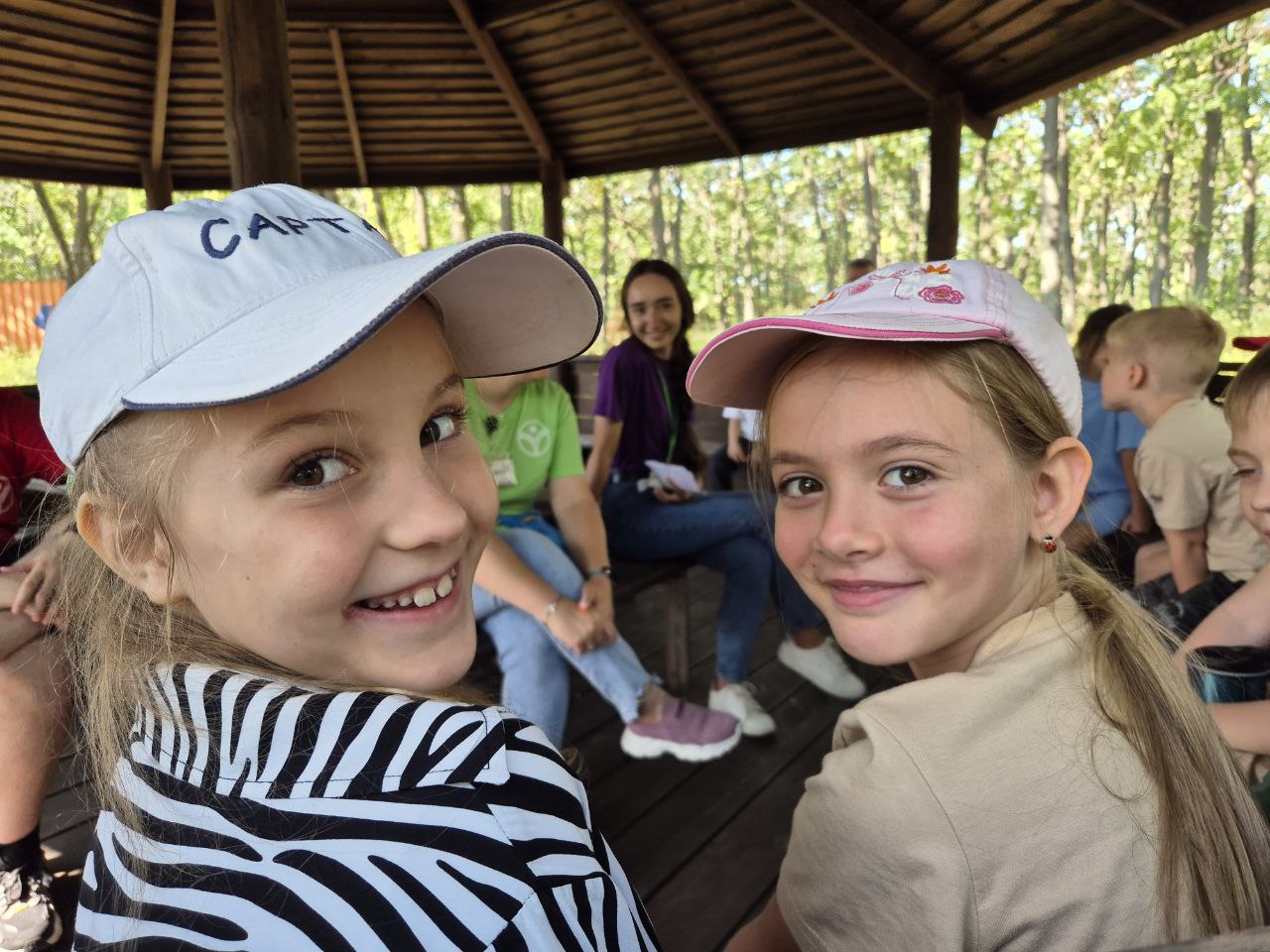 Children smiling during activity at summer camp under open pavilion