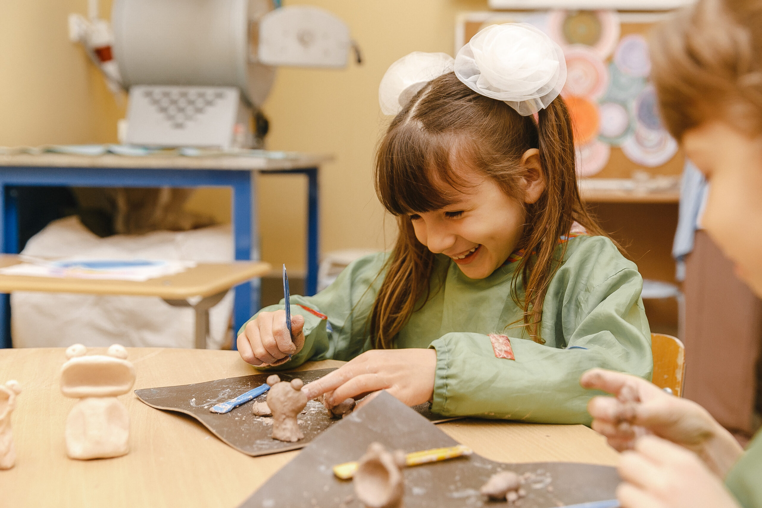 Girl smiling while sculpting clay figures at a creative class in school
