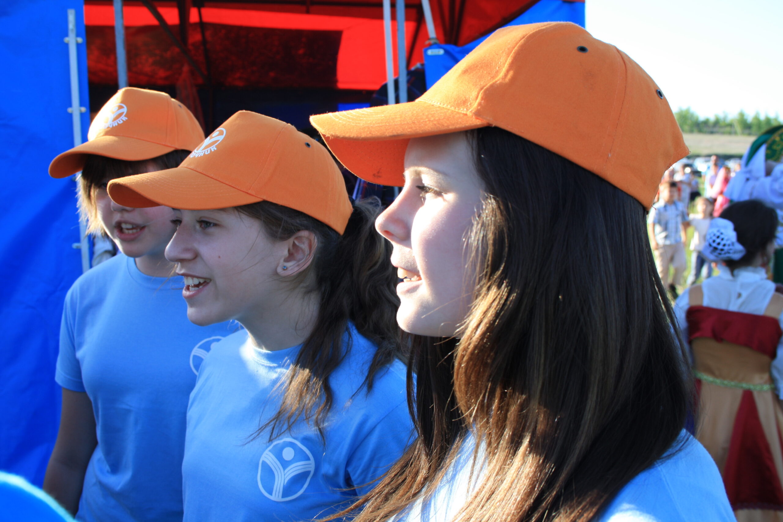 Girls wearing matching caps and t-shirts at an outdoor school event