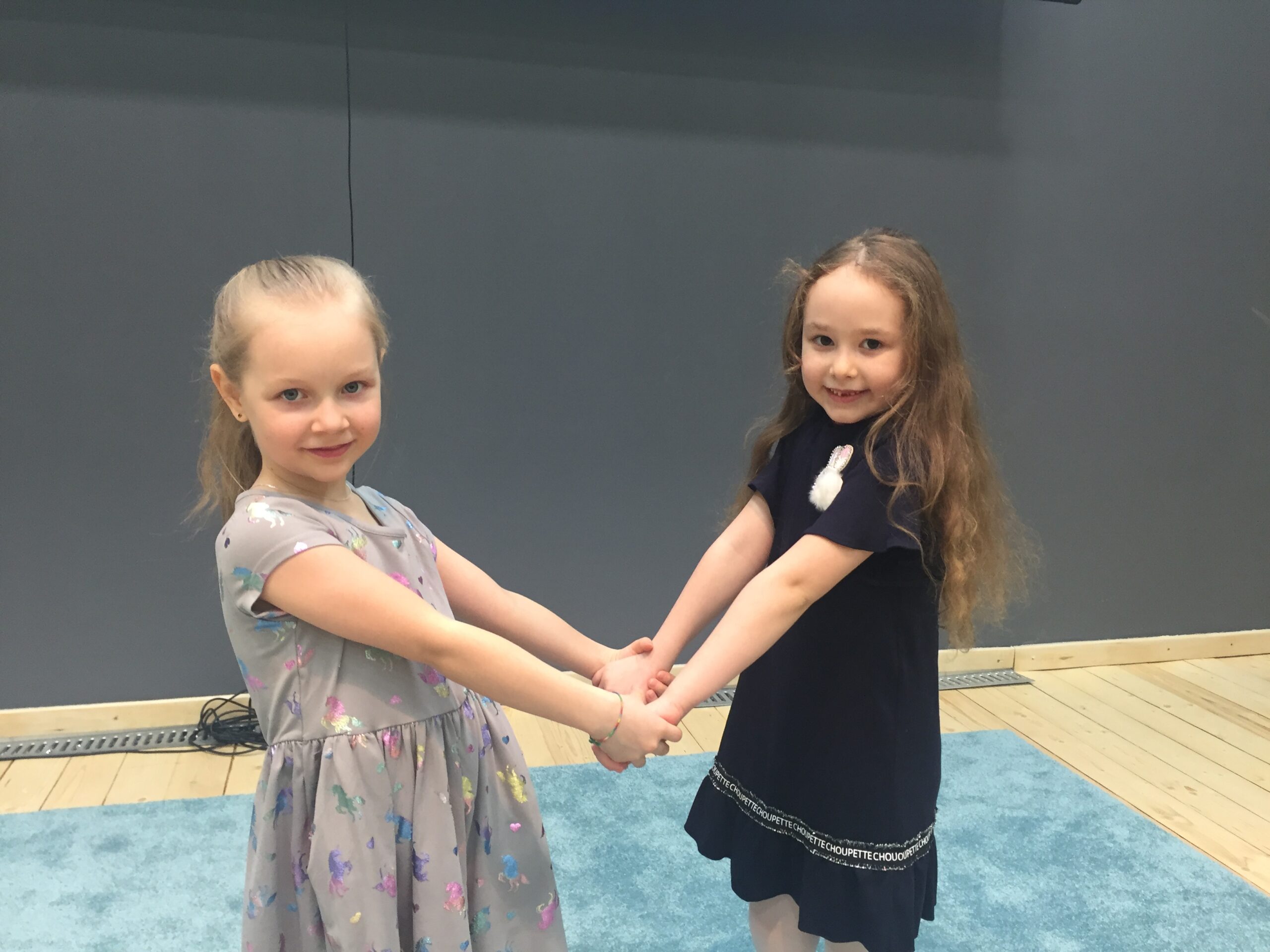 Two girls holding hands and smiling in a playroom