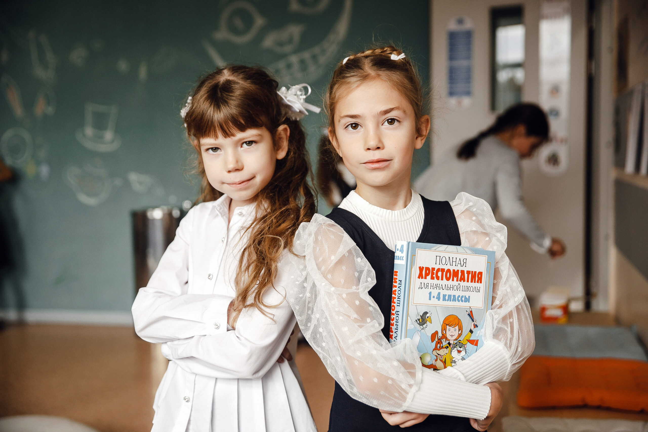 Two schoolgirls posing with a textbook in a classroom