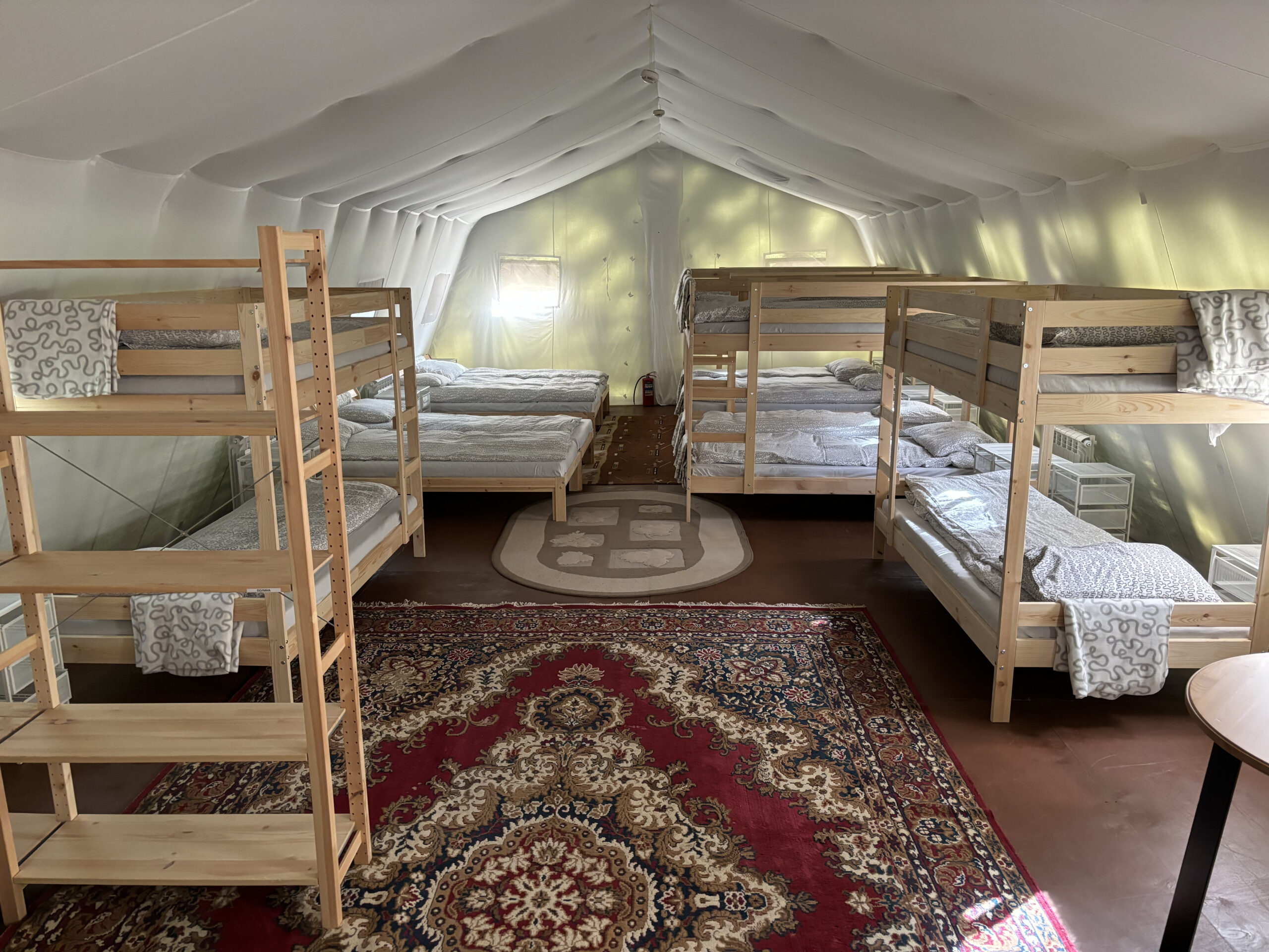 Comfortable sleeping area in a tent camp with bunk beds and rugs on the floor