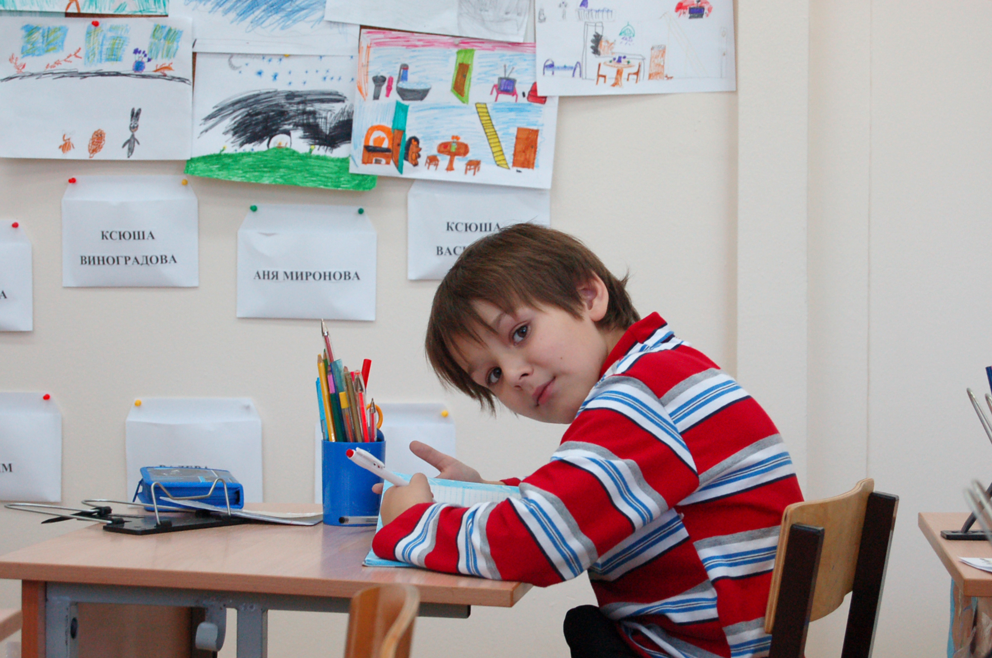 Boy writing at his desk in elementary school classroom