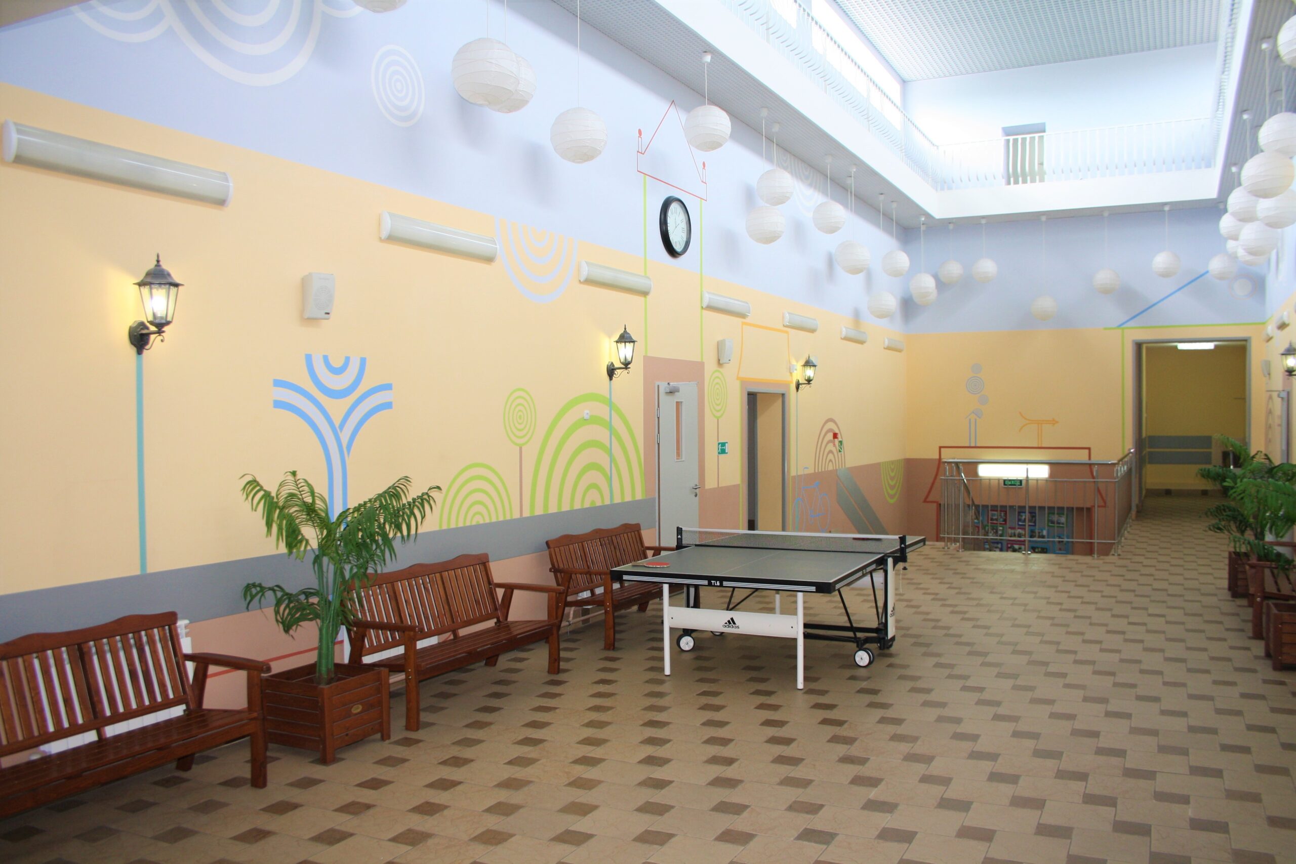 Spacious game area with ping pong table and benches in school building