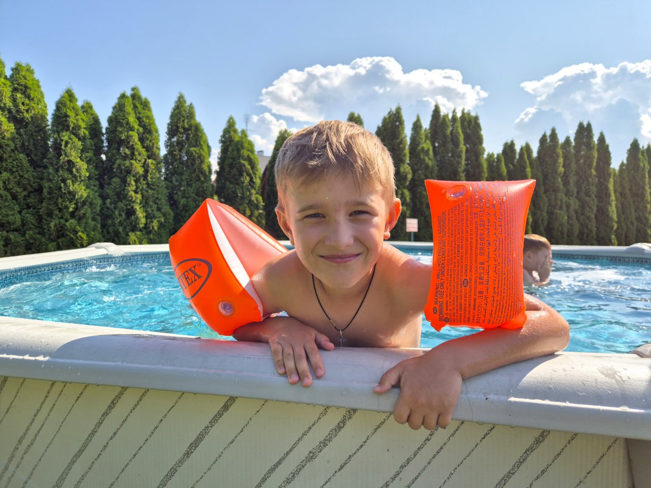 Child with floaties enjoying the pool at the outdoor camp