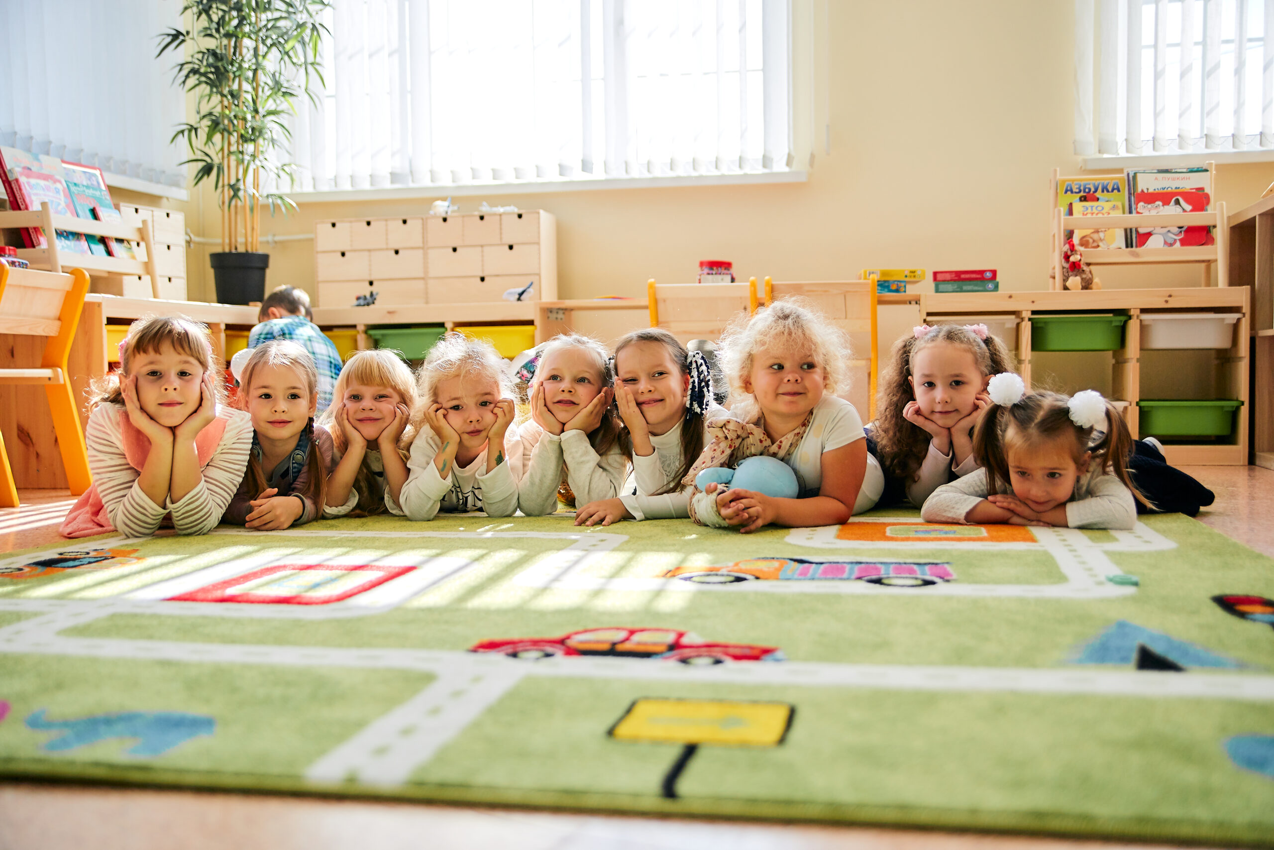 Children lying on a colorful play rug in kindergarten, smiling and resting after activities