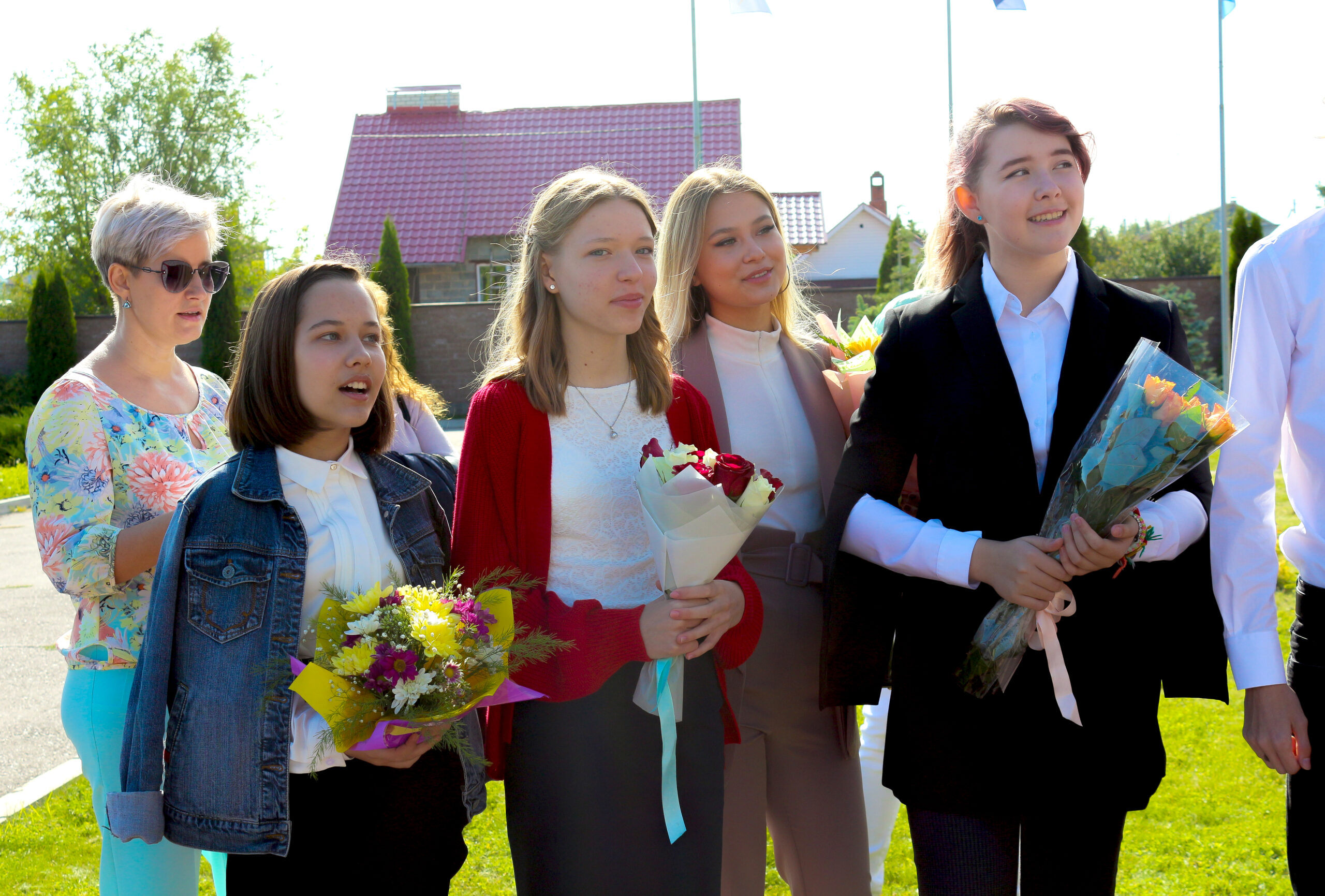 Students holding bouquets of flowers at a school ceremony