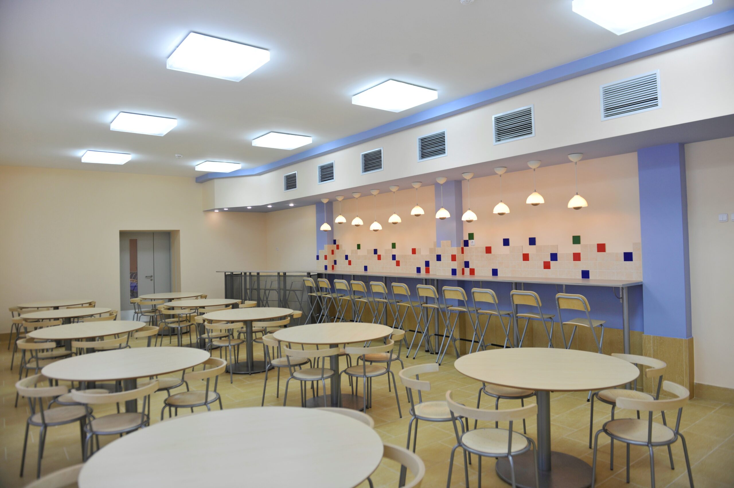 Modern cafeteria with round tables and bar seating for students