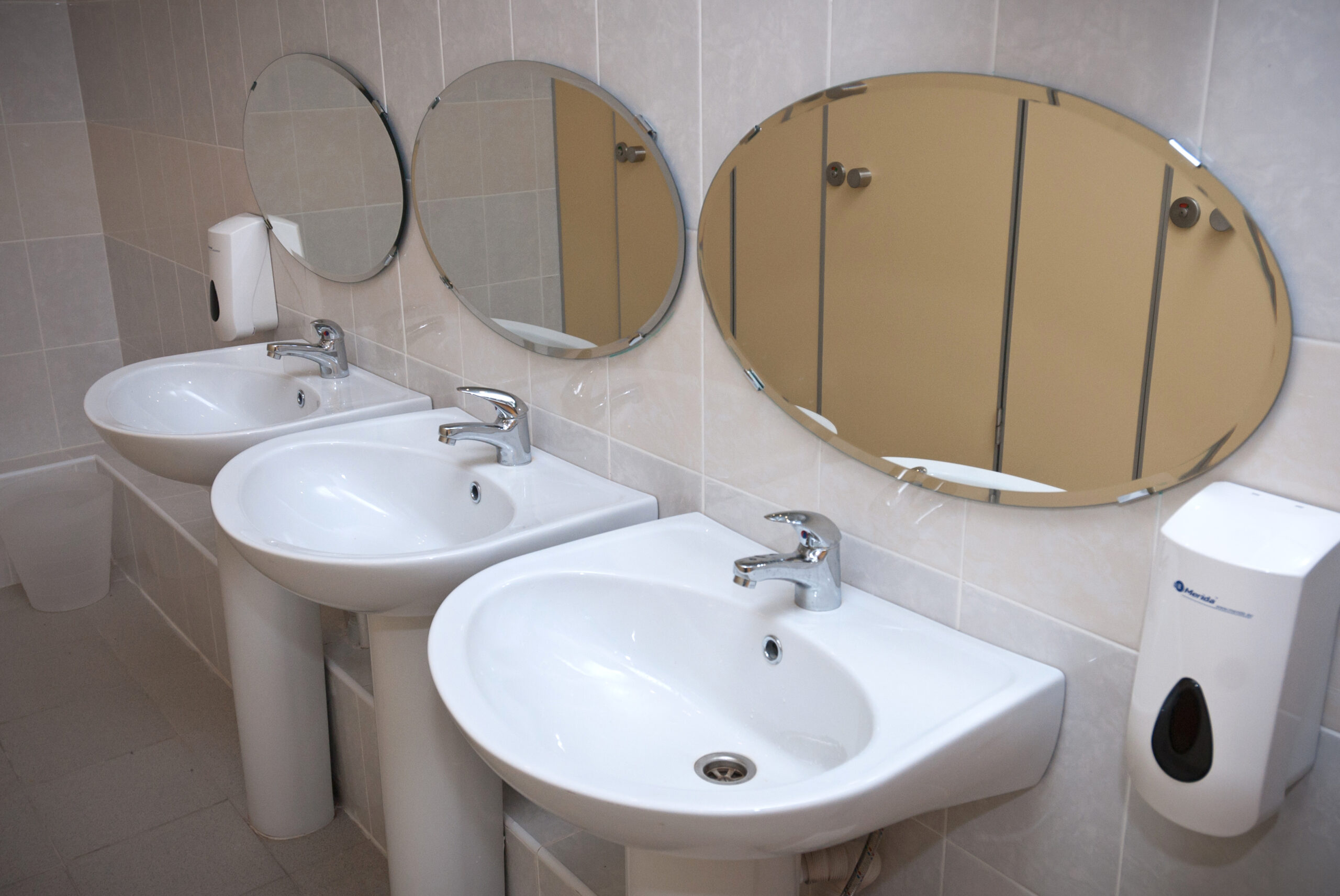 Modern wash area with three sinks and mirrors in camp restroom