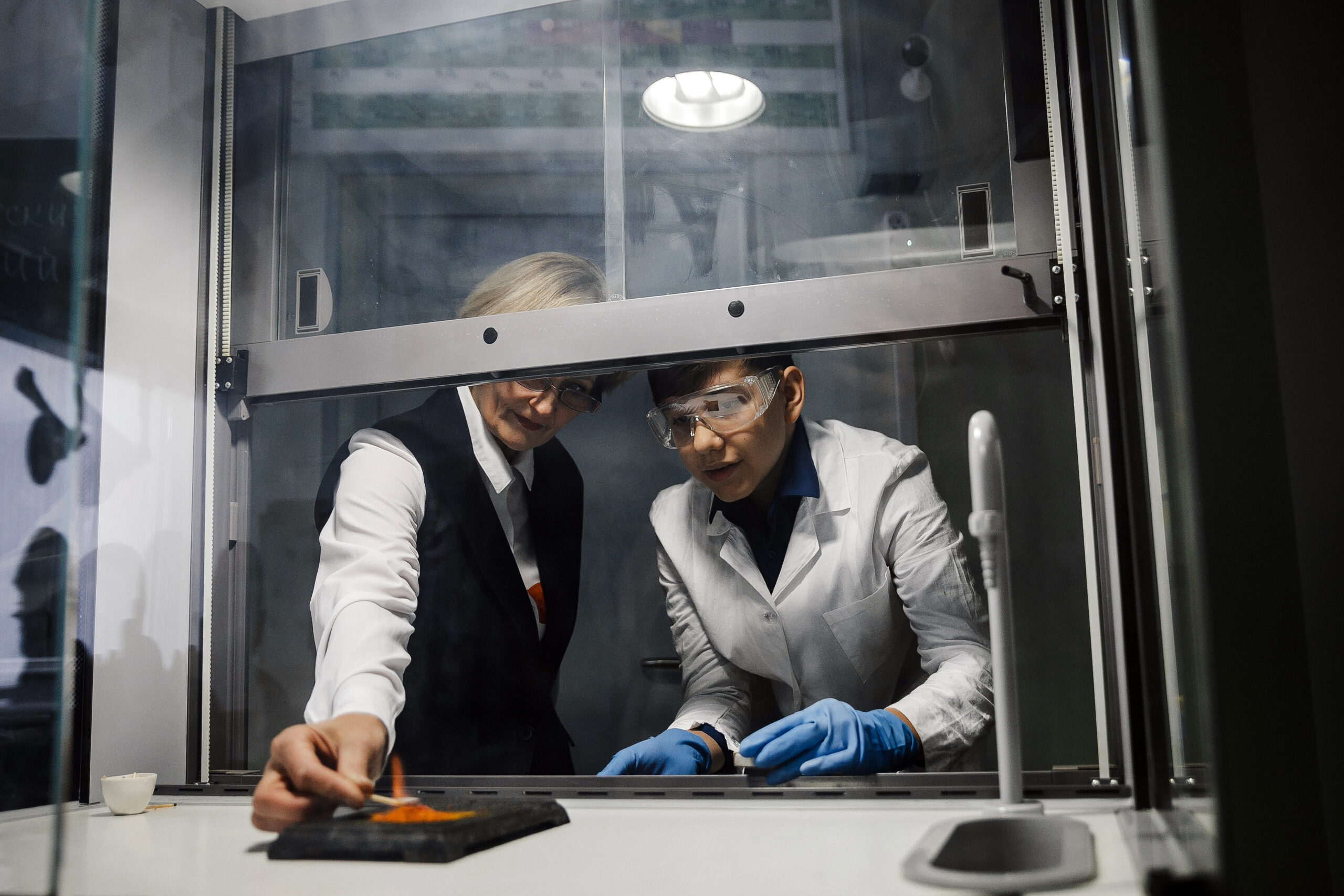 Student conducting a chemistry experiment under teacher supervision in a laboratory