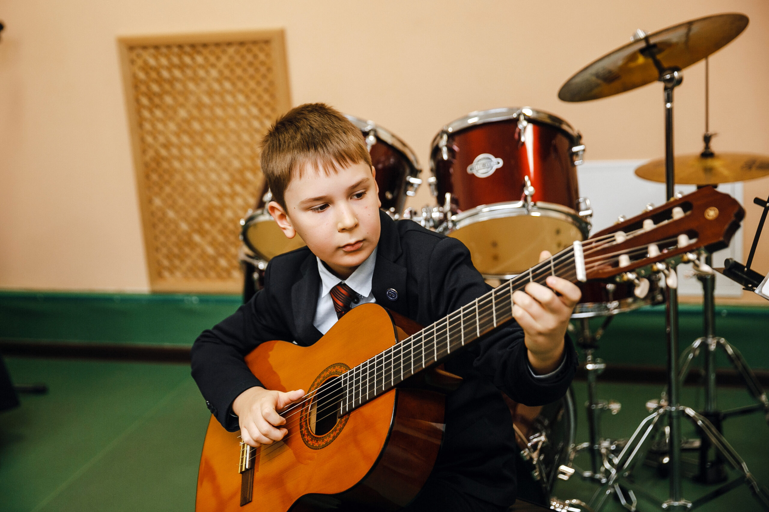 Student playing classical guitar in music classroom