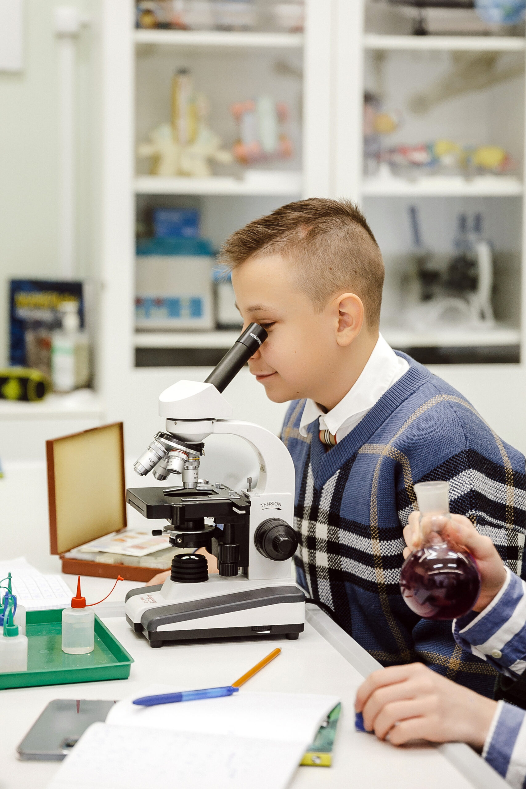 Student carefully looks through a microscope during biology lesson at school