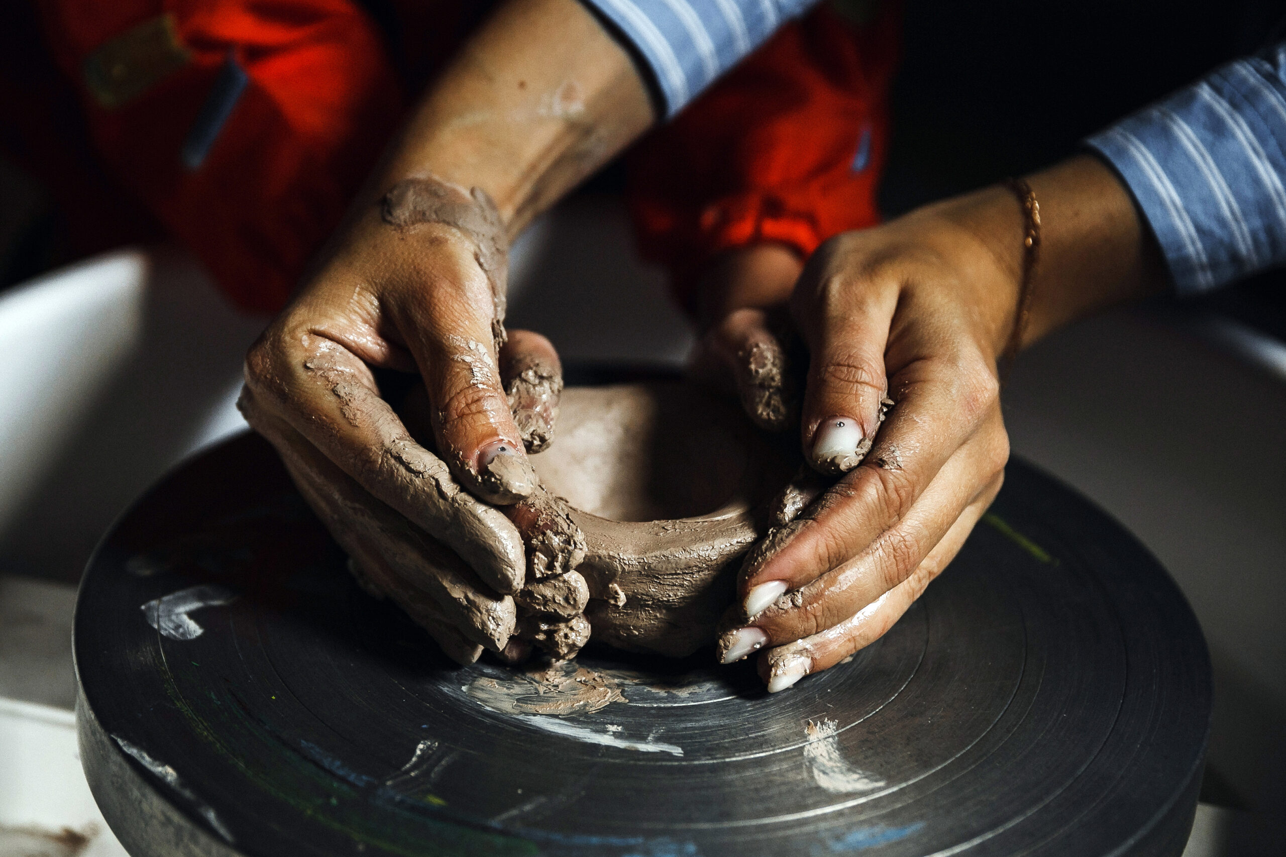 Students molding a ceramic piece on a pottery wheel at school