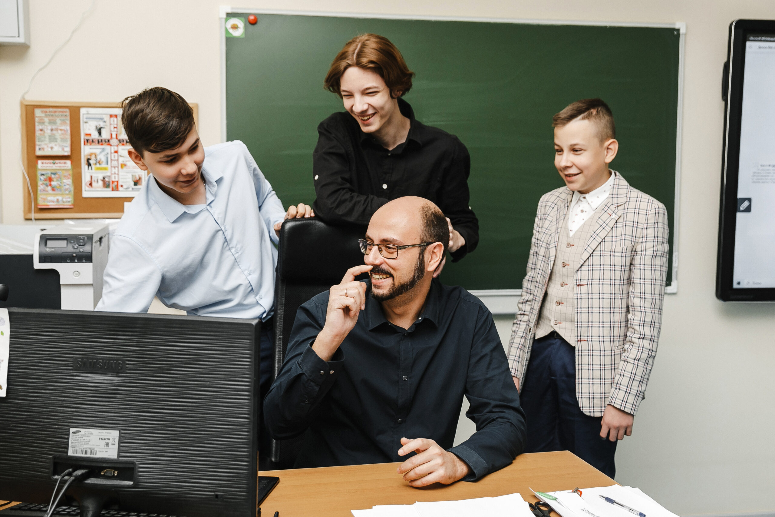 Teacher and students discussing a project by the computer in the classroom