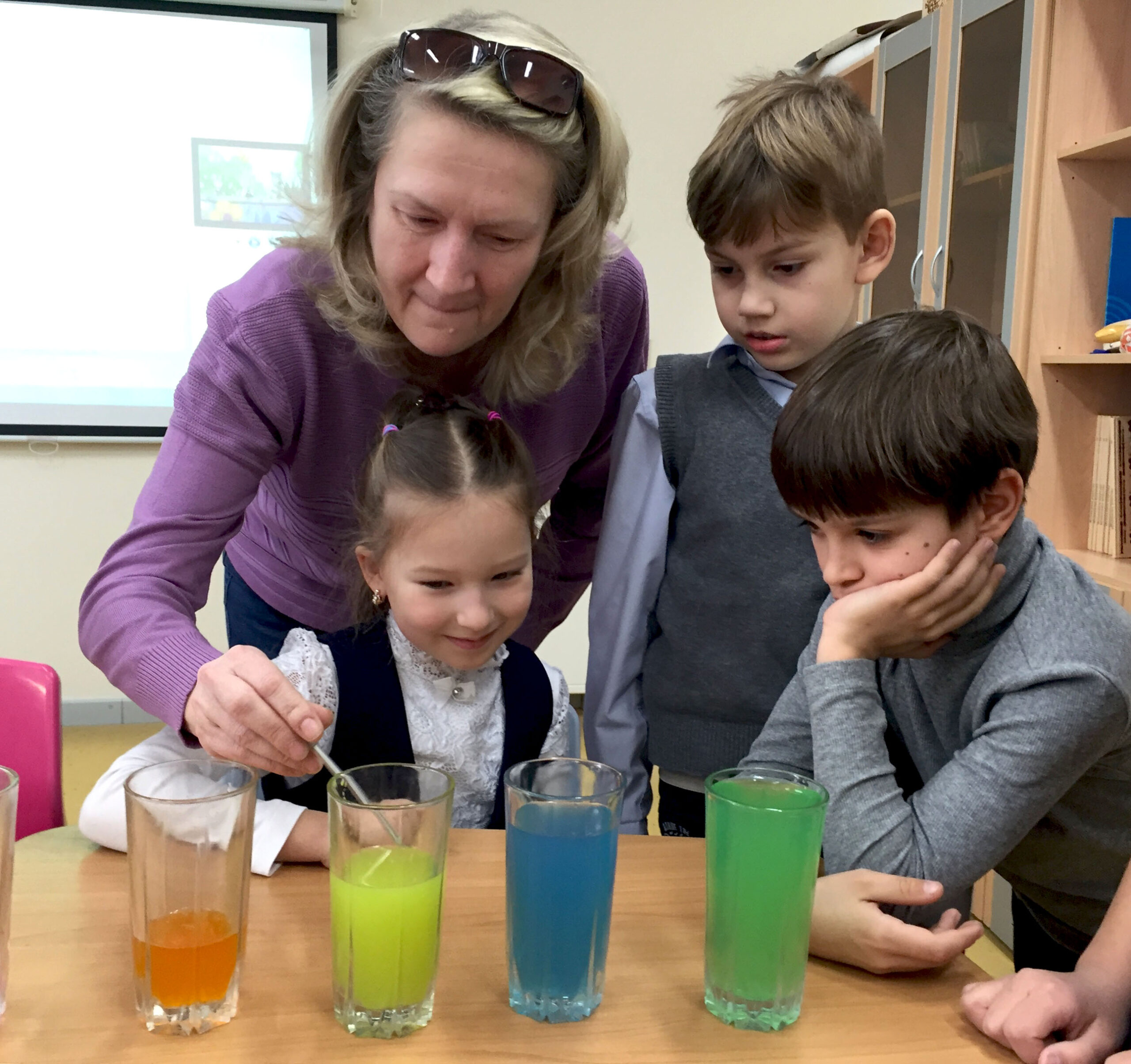 Teacher shows children an experiment with colorful liquids in the classroom