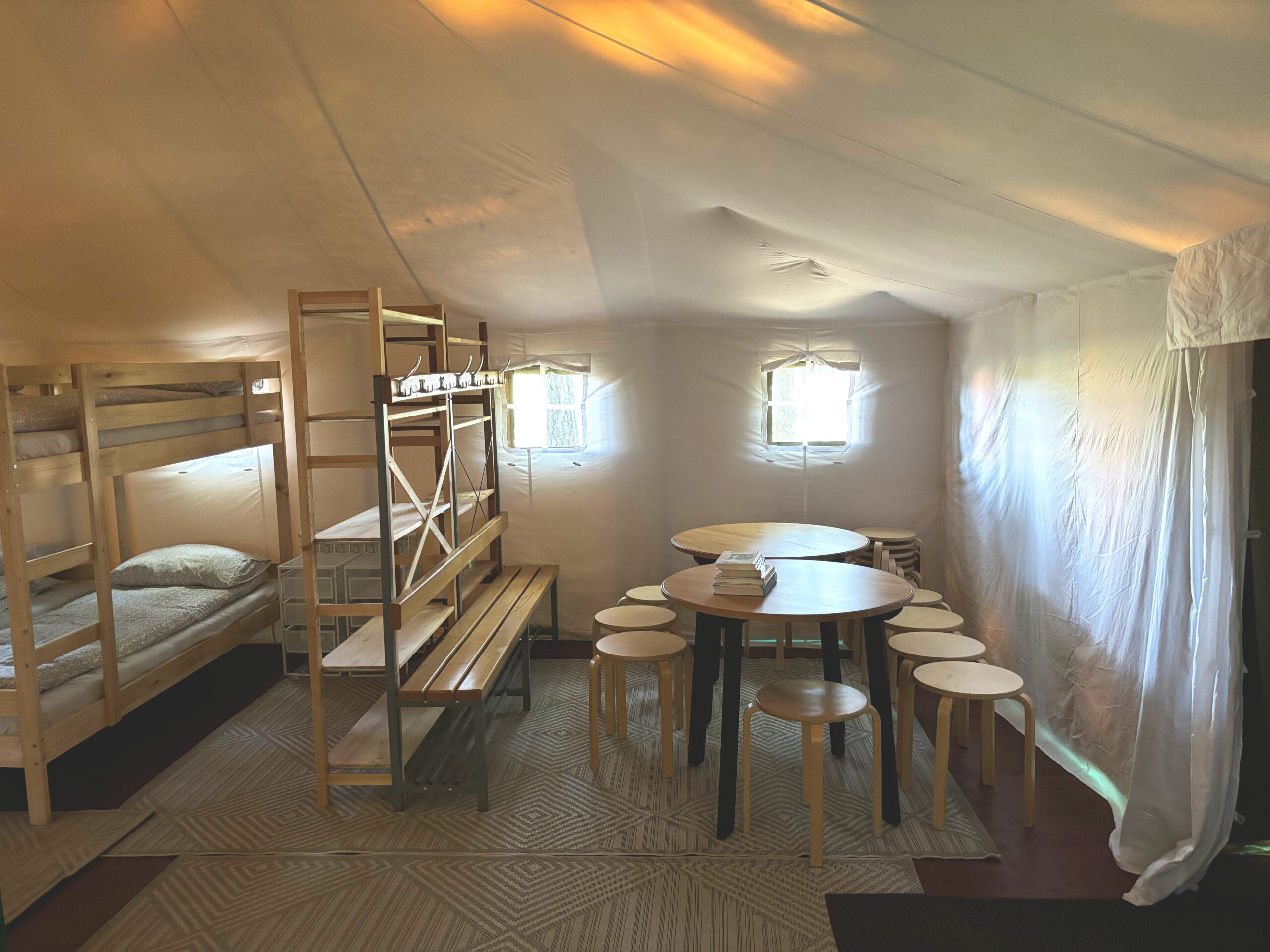 Interior space of a tent with bunk beds and tables for children’s rest